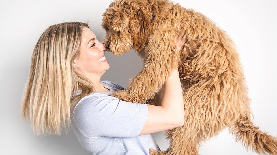 woman touching noses with goldendoodle