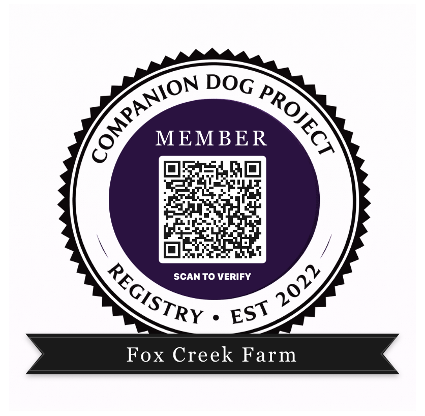 Member badge with a QR code at center, circular seal reading 'Companion Dog Project Registry Est 2022' and a black ribbon displaying 'Fox Creek Farm' below.