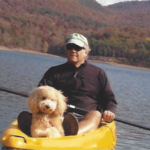 goldendoodle on kayak with man