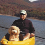 goldendoodle on kayak with man